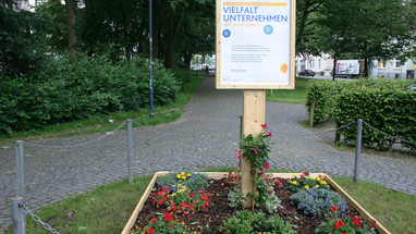 Das Emblem „Charta der Vielfalt“ ist in einem Blumenbeet gepflanzt.