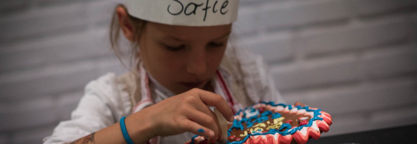 Ein Kind verziert ein Lebkuchenherz