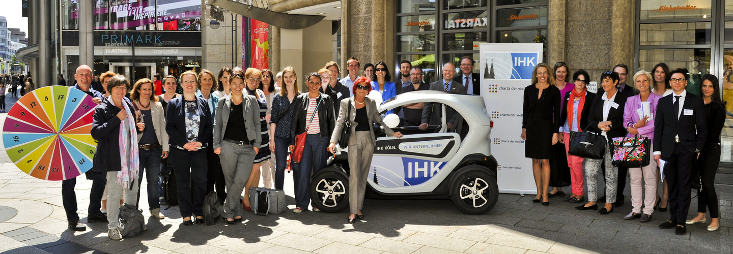 Eine Gruppe Menschen mit einem IHK-gebrandeten Smart und einem Tombola-Drehrad.