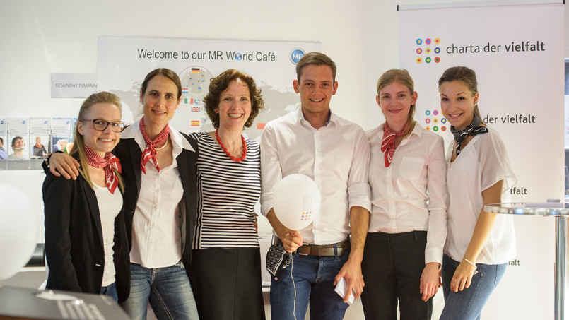 Ein Mann und 5 Frauen stehen vor Charta Aufstellern zussammen und schauen lächelnd in die Kamera.