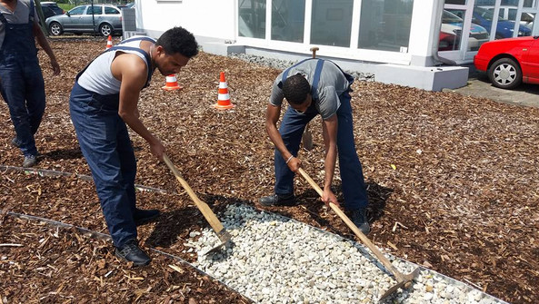 Teilnehmende von "First Step - Fulda" beim Anlegen eines Gartenwegs für den  „Garten der Vielfalt“